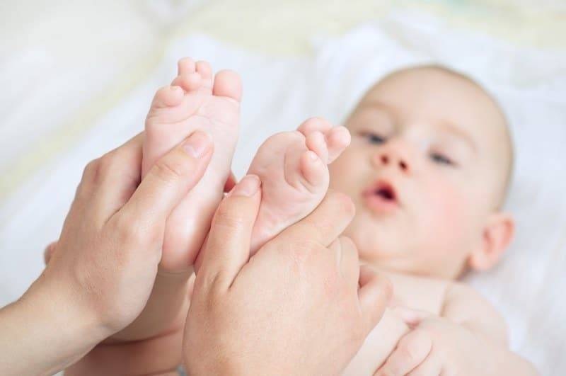 Thực hiện massage đôi chân của trẻ là động tác đầu tiên